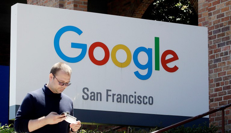 A man walks past a Google sign in San Francisco.