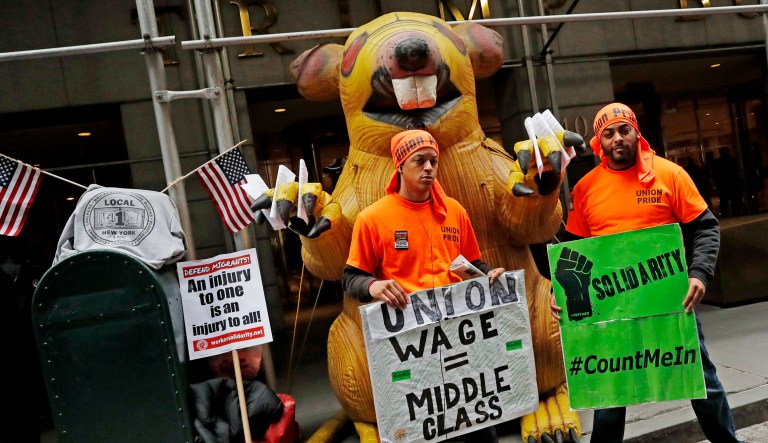 Union members stand in front of an inflatable rat with pro-union signs.