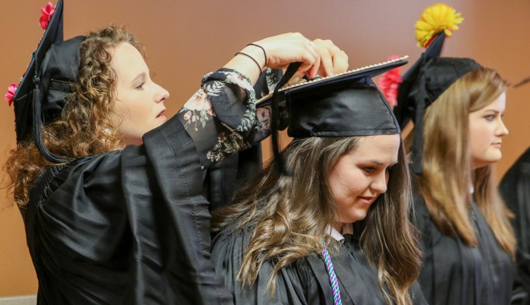 Mississippi State University-Meridian graduates Alexis Brown, left, helps Miranda Chaney with her cap prior to graduation ceremonies at the MSU Riley Center in Meridian, Miss.
