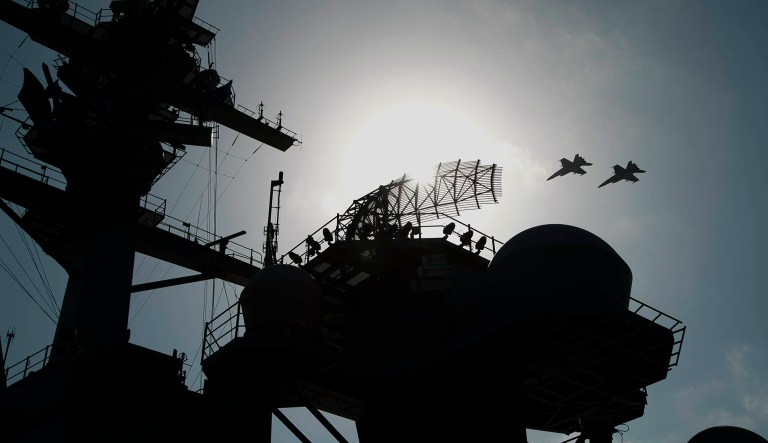 F/A-18 fighter jets fly over the deck of the USS Abraham Lincoln aircraft carrier in the Arabian Sea.