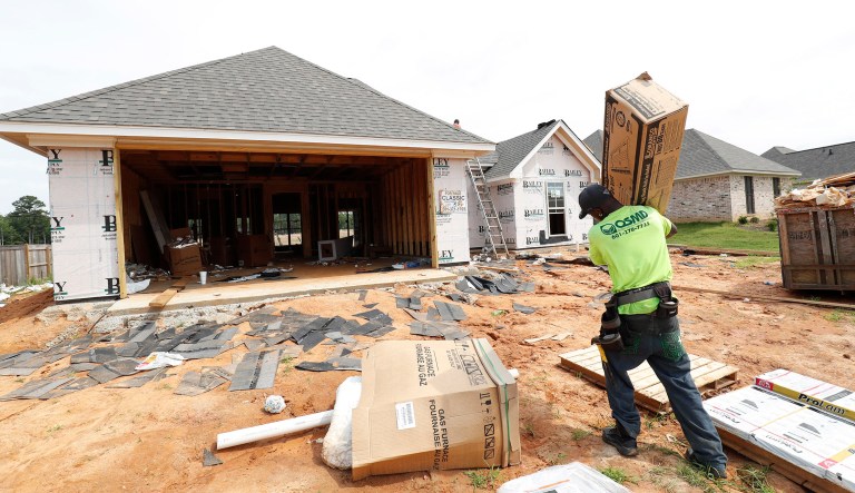 In this June 19, 2019, photo a worker carries supplies for a new house in a Brandon, Mississippi, neighborhood.
