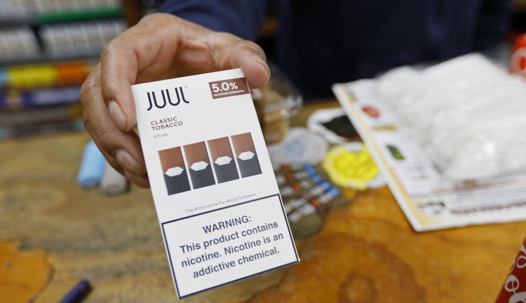 In this Monday, June 17, 2019 photo, a cashier displays a packet of tobacco-flavored Juul pods at a store in San Francisco. 