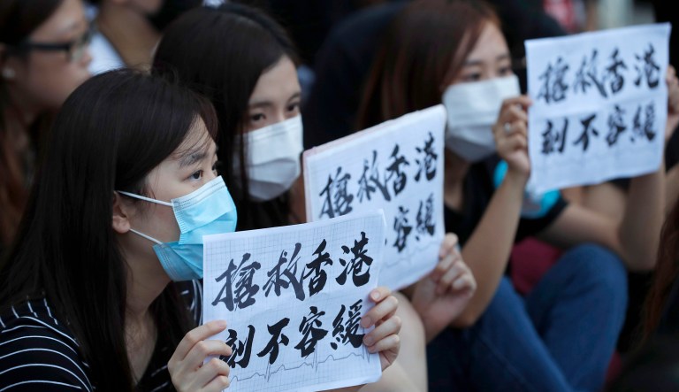 Workers from the medical and health care sector hold up signs that read: "Rescue Hong Kong, There is no time for delay" during a demonstration in Hong Kong on Friday, Aug. 2, 2019. 