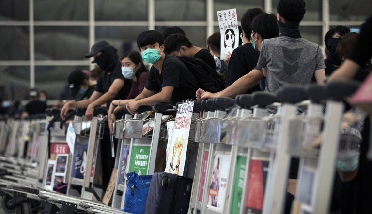 Protesters use luggage trolleys to block the departure gates during a demonstration at the Airport in Hong Kong on Tuesday. Protesters severely crippled operations at Hong Kong's international airport for a second day Tuesday, forcing authorities to cancel all remaining flights out of the city after demonstrators took over the terminals as part of their push for democratic reforms. 
