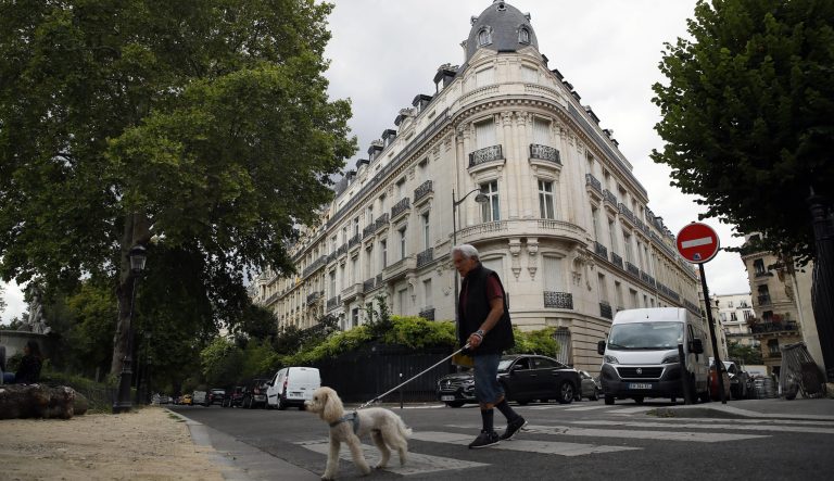 A man walks his dog next to an apartment building owned by Jeffrey Epstein in the 16th district in Paris, Tuesday, Aug. 13, 2019. 