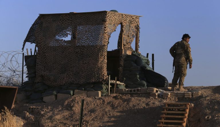 A fighter from the Syrian Democratic Forces, SDF, stands inside a post where U.S. troops were based, in Tel Abyad town, at the Syrian-Turkish border, Syria, Monday, Oct. 7, 2019. 