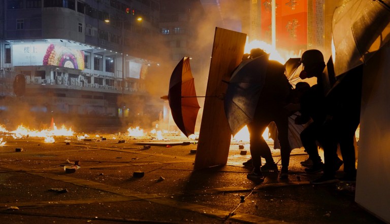 Protestors react as police fire tear gas in the Kowloon area of Hong Kong, Monday, Nov. 18, 2019. 