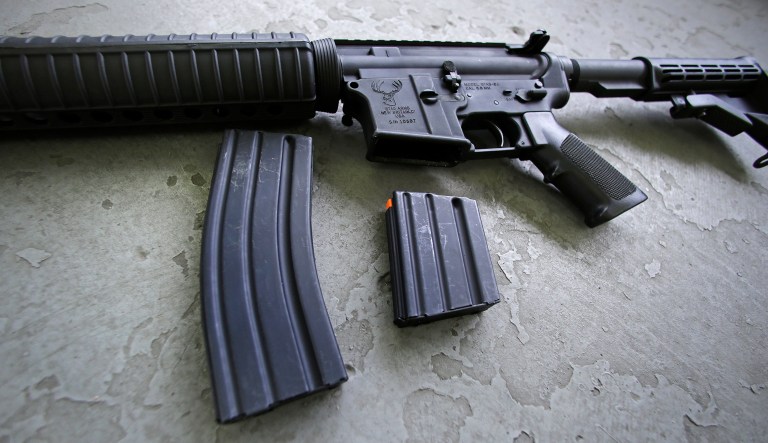 A 30 round magazine and a 10 round magazine rest below an AR-15 rifle. 
