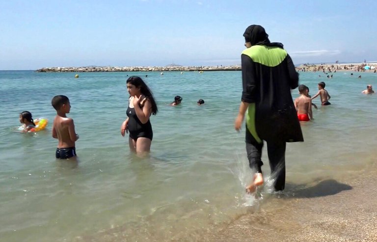 Nissrine Samali, 20, gets into the sea wearing a burkini, a wetsuit-like garment that also covers the head, in Marseille, France.