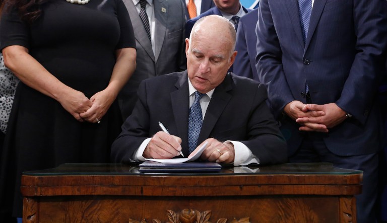 Gov. Jerry Brown signs his environmental measure SB100 into law, Sept. 10, 2018, in Sacramento, Calif.