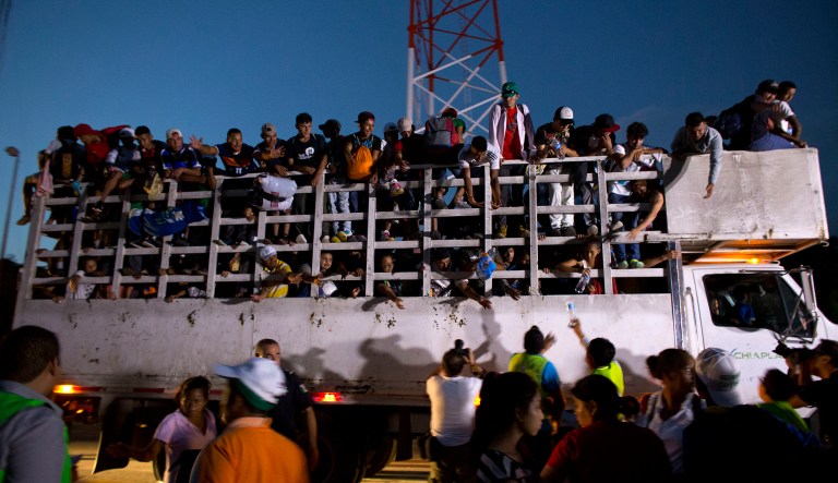 Men pass up water to Central Americans riding on the back of a truck while other migrants wait for rides, as a thousands-strong caravan of Central American makes its way toward the U.S. border, north of Pijijiapan, Mexico, at dawn on Friday, Oct. 26, 2018. Many migrants said they felt safer traveling and sleeping with several thousand strangers in unknown towns than hiring a smuggler or trying to make the trip alone. 