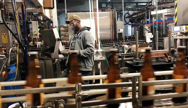 In this Jan. 14, 2019, photo, Trevor Stevens works in the bottling room at Lakefront Brewery in Milwaukee. The federal shutdown is impacting the federal agency Alcohol and Tobacco Tax and Trade Bureau, which approves licenses for new breweries, some ingredients and labels for beers sent out of state. The brewery is now waiting for the federal agency to approve the "My Turn: Chuck" beer label, so they can sell it out of state.
