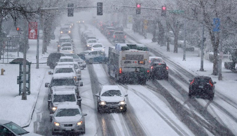 Cars and a bus make their way in the snow on Capitol Way, Friday, Feb. 8, 2019, in Olympia, Wash.