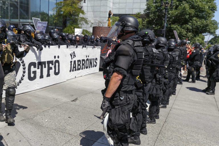 FILE - In this Aug. 4, 2018, file photo, Portland police keep Patriot Prayer affiliates separate from antifa protesters during a rally in Portland, Oregon. A member of Portland's city council says she is shocked by a newspaper report that the commander for the police rapid response team exchanged friendly text messages with a leader of far-right protests that have rocked the city. Councilwoman Jo Ann Hardesty said the reporting in Willamette Week on Thursday, Feb. 14, 2019, confirms there are members of the Portland police force who work in collusion with right-wing extremists. (AP Photo/John Rudoff, File)