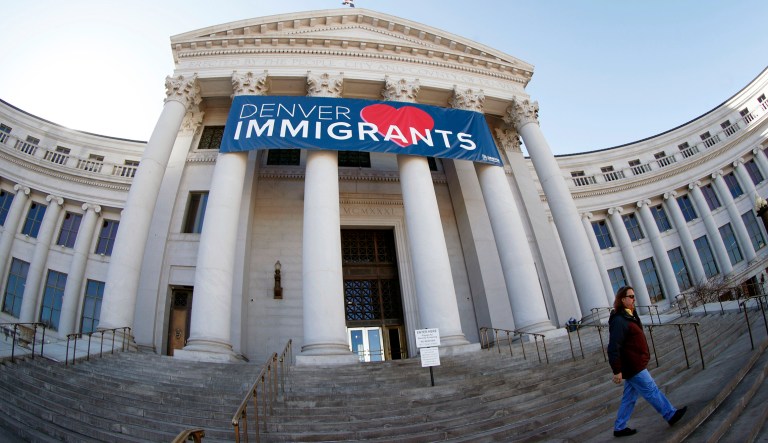 A banner to welcome immigrants is shown through a fisheye lens over the main entrance to the Denver City and County Building.