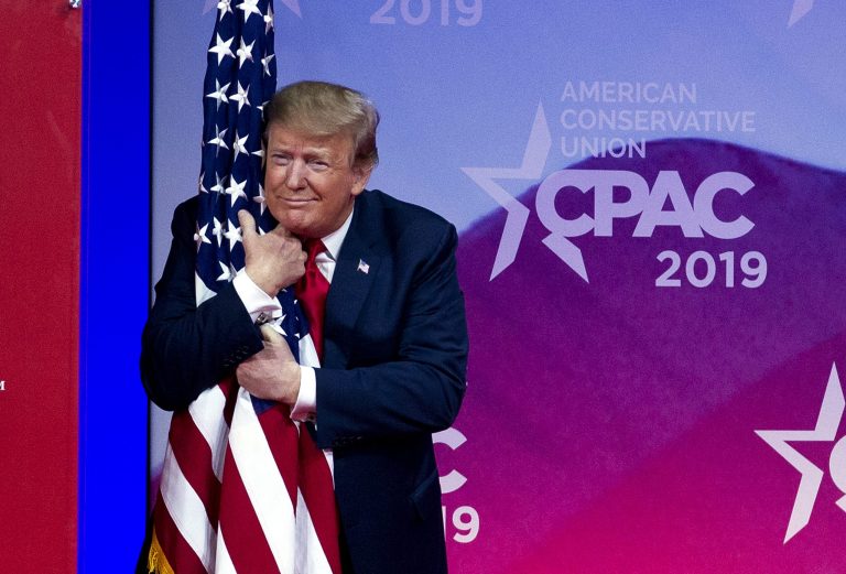 President Donald Trump hugs the American flag as he arrives to speak at Conservative Political Action Conference, CPAC 2019, in Oxon Hill, Md., Saturday, March 2, 2019.
