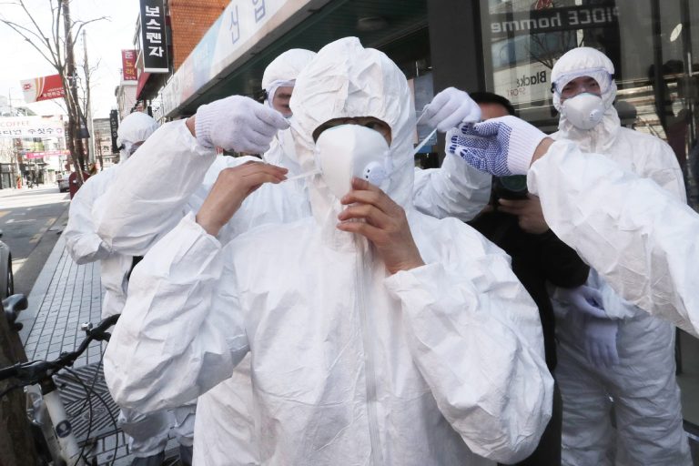 A worker wears a face mask to spray disinfectant as a precaution against the coronavirus at a shopping street in Seoul, South Korea, Thursday, Feb. 27, 2020.