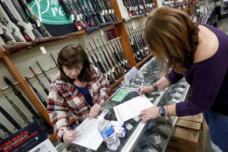 Andrea Schry, right, fills out the buyer part of legal forms to buy a handgun as shop worker Missy Morosky fills out the vendors parts at Dukes Sport Shop in New Castle, Pa. Gun sales have surged to historic numbers during the virus crisis.