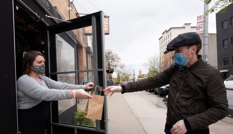 A business owner hands a bag to a client.