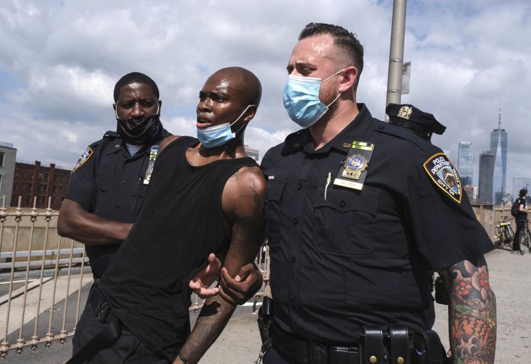 NYPD officers arrest a photographer on Brooklyn Bridge during the clash between officers and Black Lives Matter protesters, Wednesday, July 15, 2020, in New York.