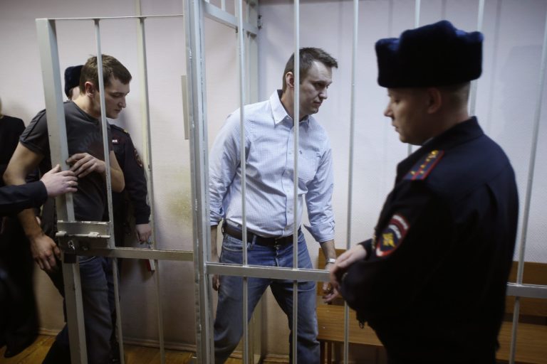 In this file photo taken on Tuesday, Dec. 30, 2014, Russian opposition activist and anti-corruption crusader Alexei Navalny, 38, second right, and his brother Oleg Navalny, left, enter into the cage at a court in Moscow, Russia.