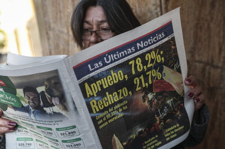 A woman reads a newspaper showing the results of the previous day's referendum in favor of rewriting the nation's constitution in Santiago, Chile, on Oct. 26. Amid a year of contagion and turmoil, Chileans turned out Sunday to vote overwhelmingly in favor of having a constitutional convention draft a new charter to replace guiding principles imposed four decades ago under the military dictatorship of Gen. Augusto Pinochet. 