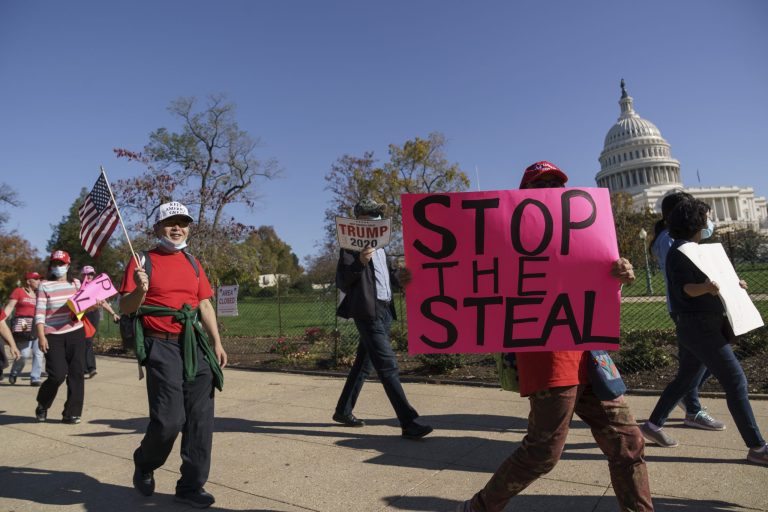 Supporters of former President Donald Trump carry flags and signs as they parade past the Capitol in Washington after news that  Joe Biden had defeated the incumbent in the race for the White House, in Washington, Saturday, Nov. 7, 2020.
