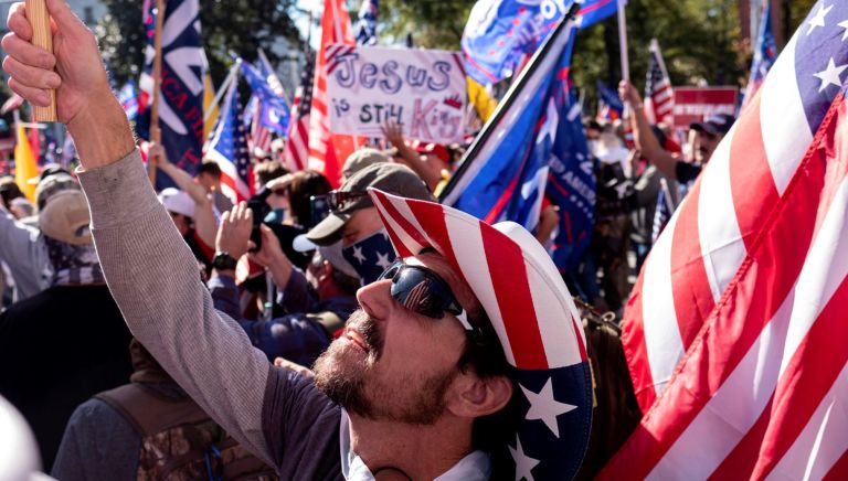 Rusty Albietz, of Blairsville, Ga., looks up at his flag while rallying with supporters of President Donald Trump outside of the Georgia State Capitol in Atlanta.