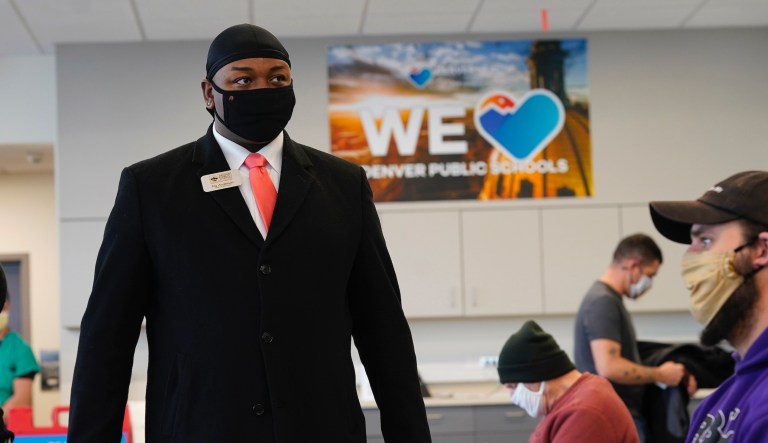 Tay Anderson, left, an at-large member of the Denver Public School board, checks on a school employee after he received a COVID-19 vaccination during a mass vaccination of 1,000 employees of Denver Public Schools including teachers, administrators, custodial workers and bus drivers at Denver Health Saturday, Feb. 13, 2021, in Denver.