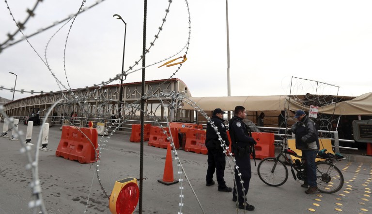 In this March 21, 2020, file photo, U.S. border agents question a man traveling on a bicycle on an international bridge at the U.S-Mexico border that joins Ciudad Juarez and El Paso, Texas.