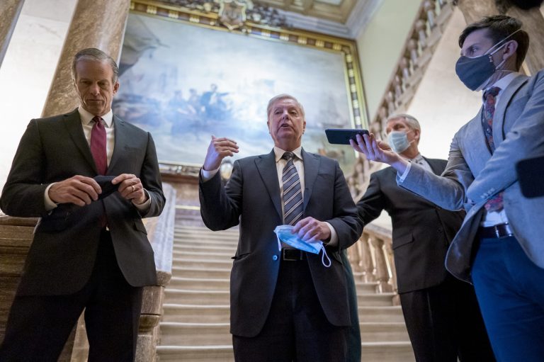 Senate Minority Whip John Thune, R-S.D., left, and Sen. Lindsey Graham, R-S.C., center, pause outside the Senate chamber to talk with reporters during a delay in work on the Democrats' $1.9 trillion COVID-19 relief bill Friday.