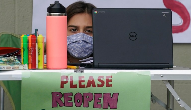 In this Feb. 18, 2021, file photo, Clarendon Alternative Elementary School fourth grader Ayla Einhorn works on her computer as students and parents attend distance learning Zoom classes at Midtown Terrace Playground in San Francisco.