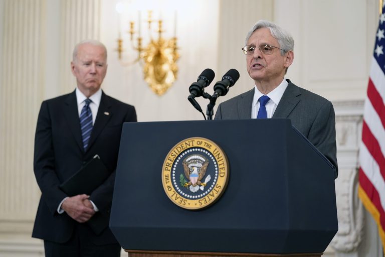 President Joe Biden listens as Attorney General Merrick Garland speaks during an event in the State Dining room of the White House.