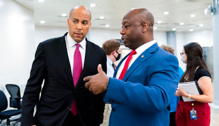 Sen. Tim Scott (R-SC), right, and Sen. Cory Booker (D-NJ) talk as they wait for a Senate subway train on Capitol Hill in Washington, Friday, July 30, 2021. 