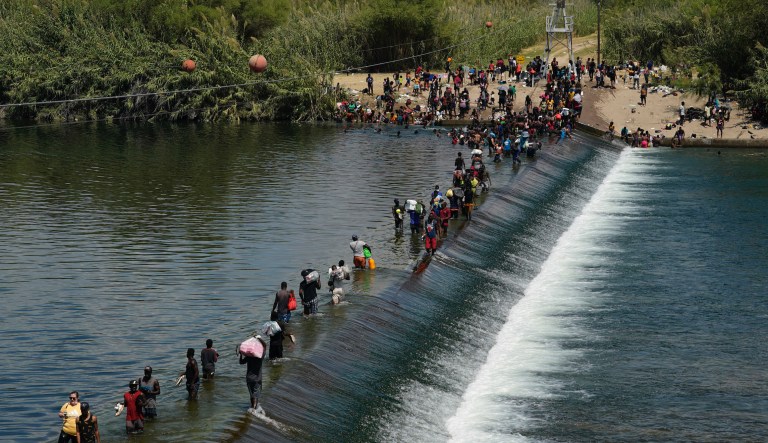Haitian migrants use a dam to cross into and from the United States from Mexico, Saturday, Sept. 18, 2021, in Del Rio, Texas.