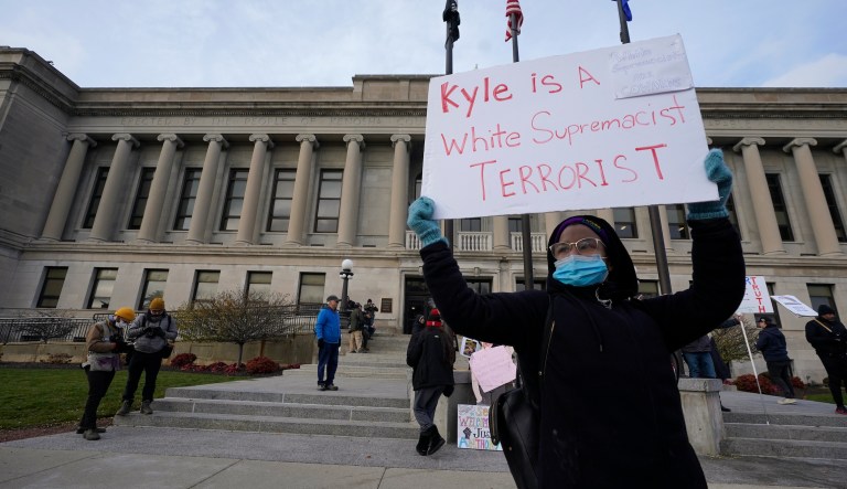 A protester stands outside the Kenosha County Courthouse, Tuesday, Nov. 16, 2021 in Kenosha, Wis., during the Kyle Rittenhouse murder trial. Rittenhouse is accused of killing two people and wounding a third during a protest over police brutality in Kenosha, last year.
