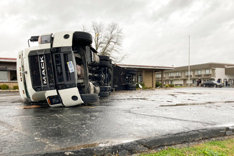 A large semi-trailer is flipped over and pushed against a building in Bowling Green, Kentucky, on Saturday after a major storm.
