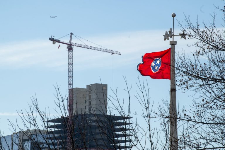 The state flag flies at the Tennessee Bicentennial Capitol Mall State Park as a construction crane hovers over a structure rising downtown, Friday, Feb.11, 2022, in Nashville, Tenn. (AP Photo/John Amis)