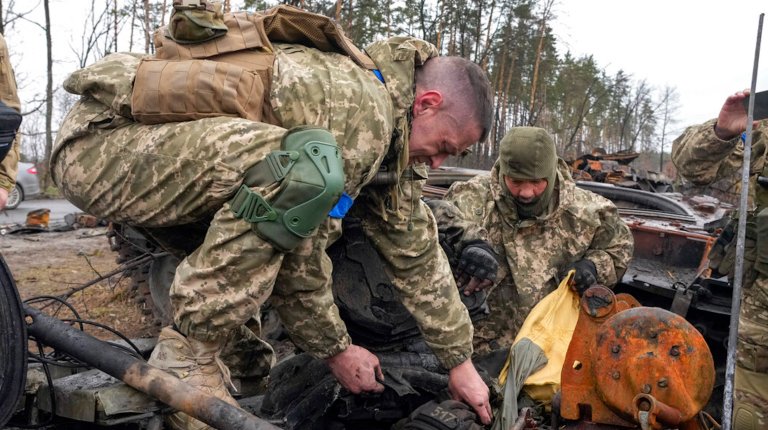 Ukrainian soldiers try to pull a dead body of a Russian soldier from the destroyed Russian tank in the village of Dmytrivka close to Kyiv, Ukraine, Saturday, Apr. 2, 2022. At least ten Russian tanks were destroyed in the fighting two days ago in Dmytrivka.