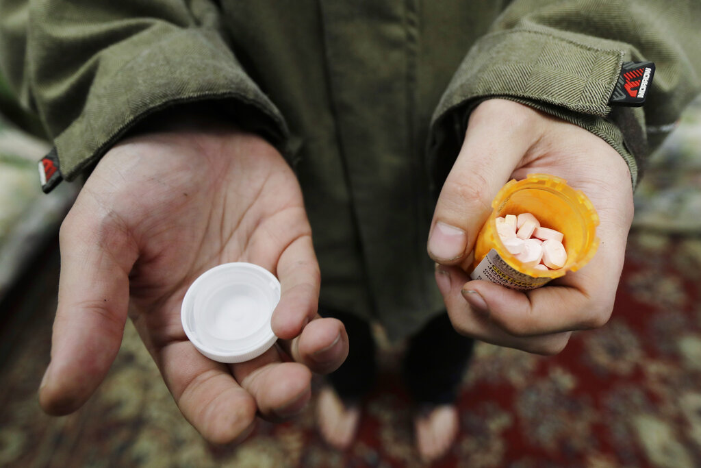 FILE - In this Nov. 14, 2019, photo, Jon Combes holds his bottle of buprenorphine, a medicine that prevents withdrawal sickness in people trying to stop using opiates, as he prepares to take a dose in a clinic in Olympia, Wash. The U.S. Department of Justice made clear, Tuesday, April 2, 2022, that barring the use of medication treatment for opioid abuse is a violation of federal law.