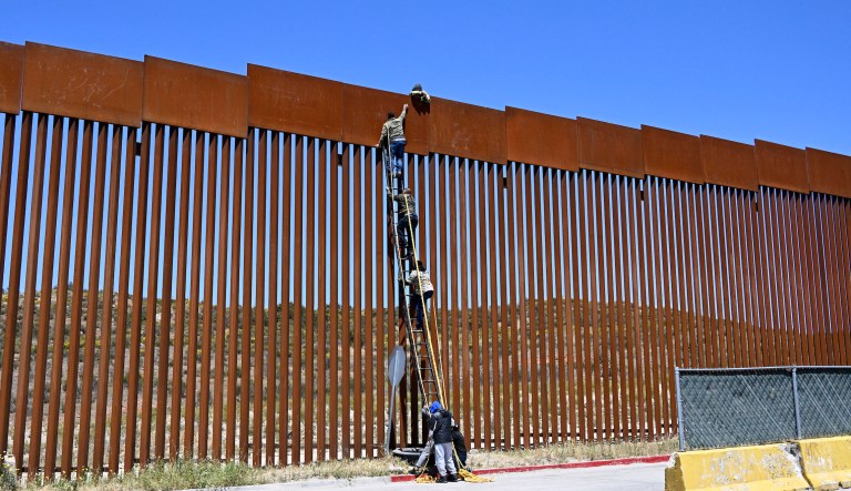 People use a ladder to scale the border fence at the US/Mexico border in Tecate, Mexico, Thursday, April 21, 2022.