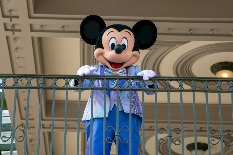 An actor dressed as Mickey Mouse greets visitors at the entrance to Magic Kingdom Park at Walt Disney World Resort.