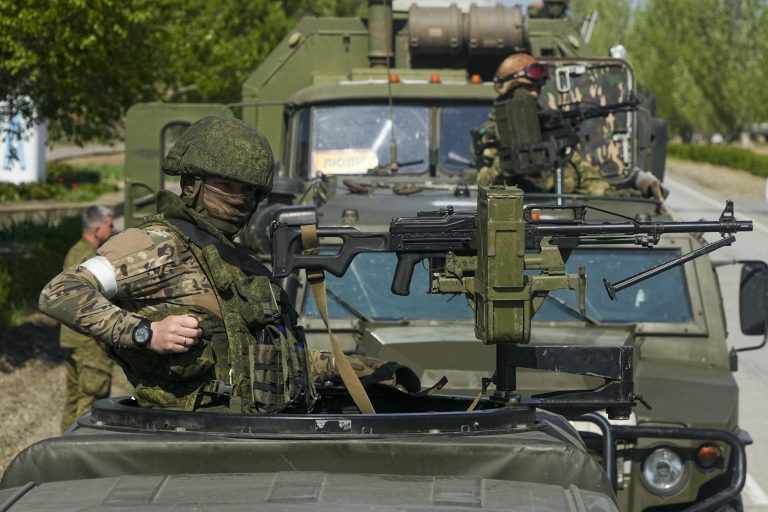 Armed Russian servicemen stand atop their military vehicles near the Zaporizhzhia Nuclear Power Station.
