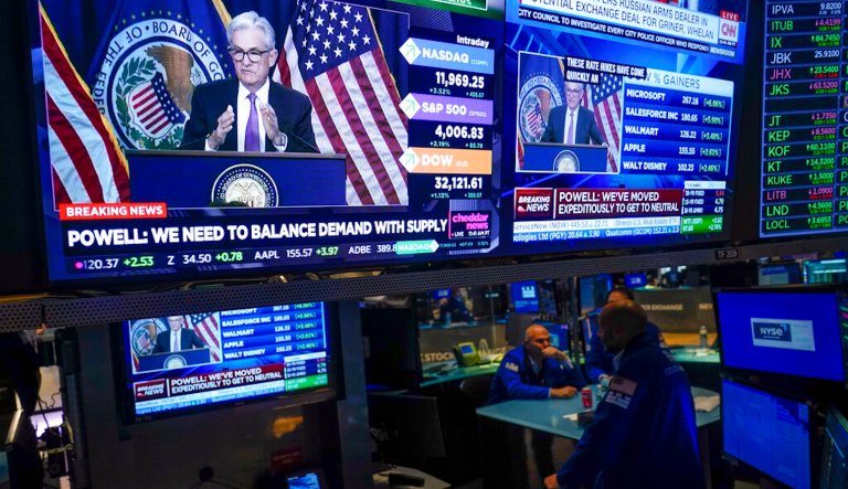 As traders work and watch, a news conference held by Federal Reserve Chair Jerome Powell is displayed at the New York Stock Exchange in New York, Wednesday, July 27, 2022.
