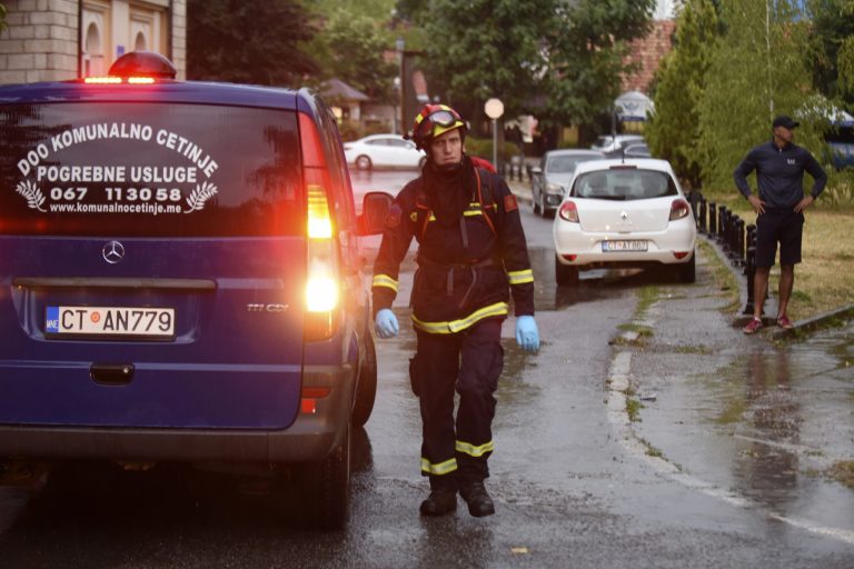 A firefighter walks by a hearse on the site of the attack in Cetinje, 36 kilometers (22 miles) west of Podgorica, Montenegro, Friday, Aug. 12, 2022. A man in Montenegro went on a shooting rampage after a family dispute, killing 11 people on the streets of a city before being shot dead in a gun battle with police.