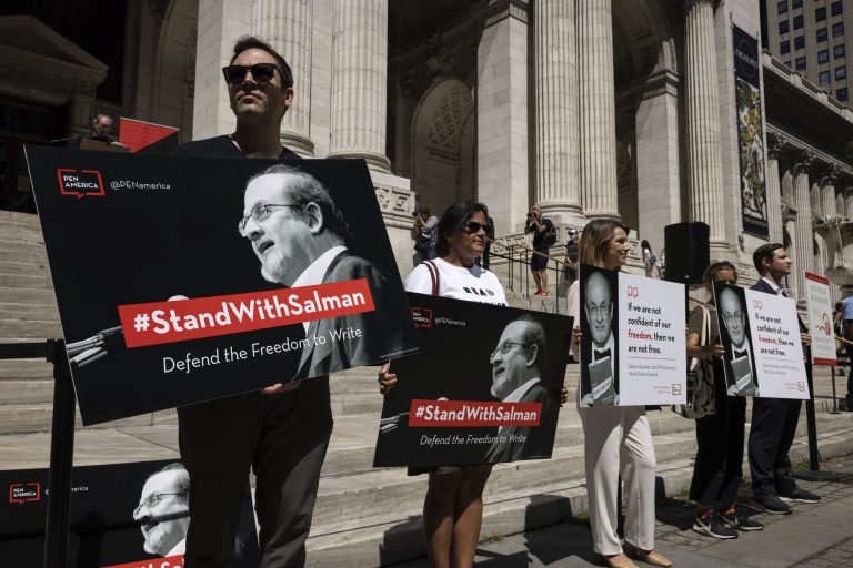Participants hold signs during a reading event in solidarity of support for author Salman Rushdie outside the New York Public Library on Aug. 19.