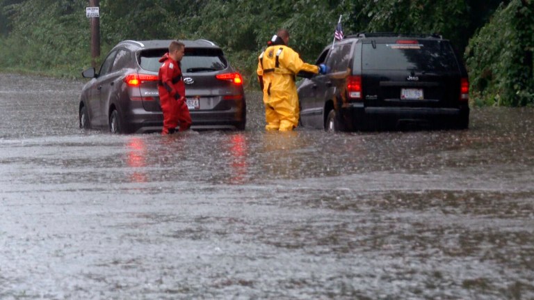 Firefighters wade through flooded Oaklawn Avenue in Cranston, R.I., to check on drivers on Sept. 5. The heavy rain that caused street flooding and forced the closure of major roads in Rhode Island on Labor Day continued on Tuesday, according to the National Weather Service.   