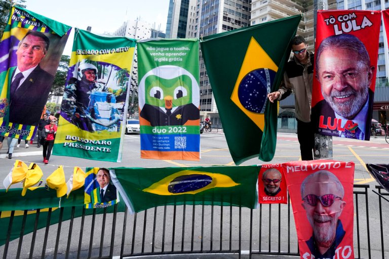 A man sells flags during general elections in Sao Paulo, Brazil, Sunday, Oct. 2, 2022. For sale are Brazil national flags and of Presidential candidates, the incumbent Jair Bolsoaro and former president Luiz Inacio 