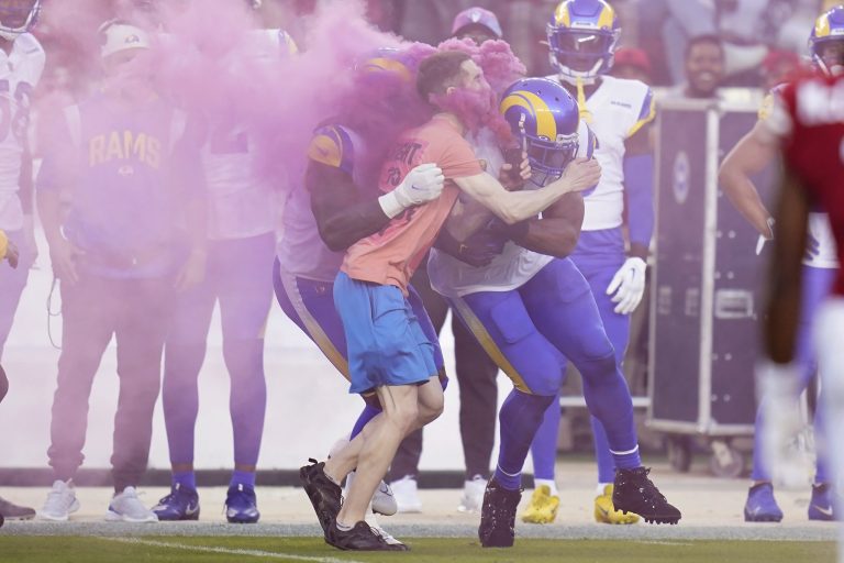 A protester is hit by Los Angeles Rams defensive end Takk McKinley, middle left, and linebacker Bobby Wagner.