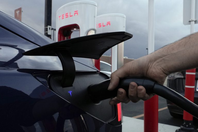 A motorist charges his electric vehicle at a Tesla Supercharger station in Detroit, Wednesday, Nov. 16, 2022. 